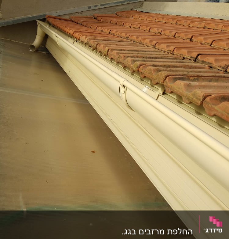 רעפים חומים על גג עם מרזב לבן